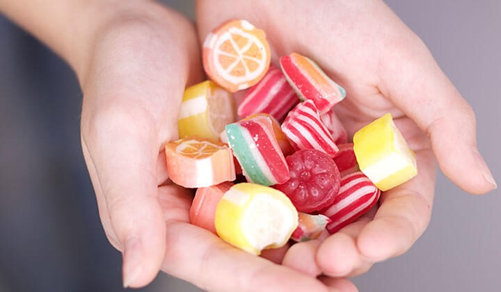 Ruka so sladkosťami Gingivitída z cukru